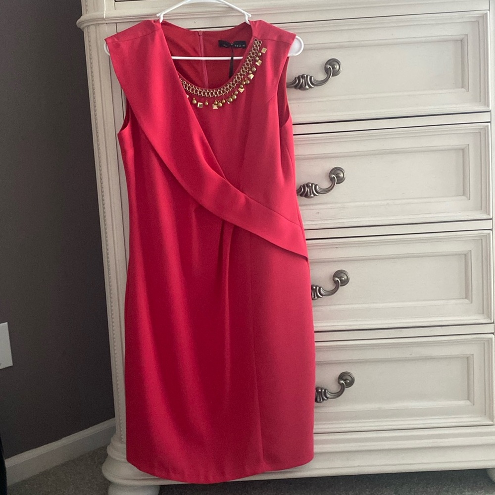 Beautiful and elegant red dress, knee length , has a golden chain on neck area.